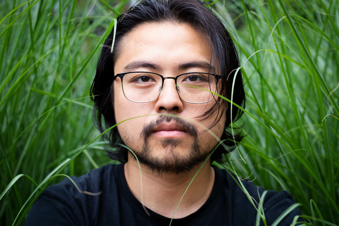 Portrait von Theaterregisseur Dan Thy Nguyen im hohen Gras.