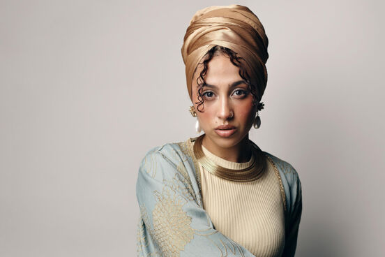 Tua El-Fawwal trägt einen goldfarbenen Hijab, ein beiges Oberteil und ein hellblau-goldene Robe und Goldschmuck
